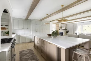 Open kitchen and living room space with beams across ceiling and large center island