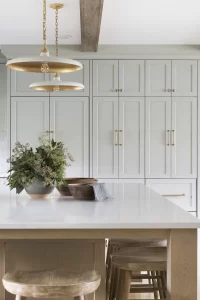 Custom built in light grey cabinetry with gold hardware behind a large built in island
