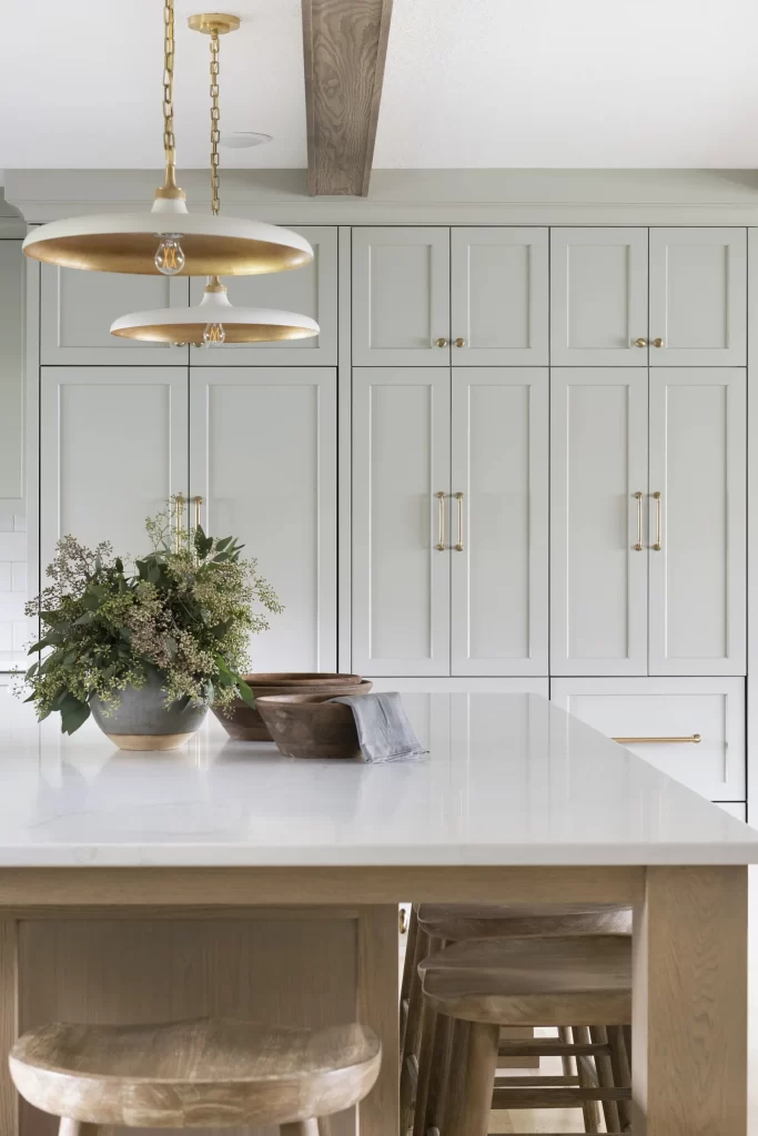 Custom built in light grey cabinetry with gold hardware behind a large built in island