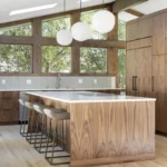 kitchen remodel with handmade globe lighting over large island; dark wood cabinets and window trim; light oak flooring throughout